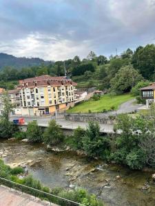 a building next to a river next to a building at Apartamento con vistas a la montaña in Infiesto