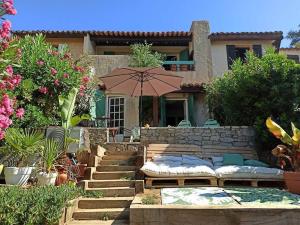 a house with a patio with an umbrella and benches at Mas Flora in La Croix-Valmer