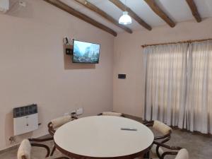 Habitación con mesa blanca, sillas y TV. en Alojamiento Mesas en San Rafael