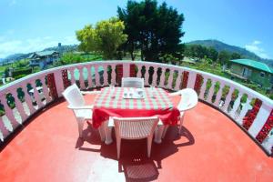 una mesa y sillas rojas y blancas en el balcón en Heavenly Home Inn, en Nuwara Eliya