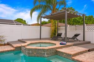 a swimming pool with a patio with two chairs and an umbrella at Tropical Oasis FL Pinellas Park in Pinellas Park