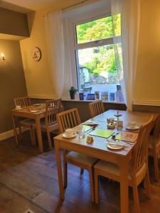 a dining room with two tables and a window at Elton Guest House in Grange Over Sands