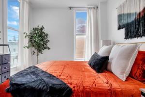 a bedroom with an orange bed with pillows and a window at Swanky Downtown Suite Unit 2 near Proctors Theater in Schenectady