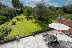 an outdoor patio with an umbrella and a lawn at Contemporary Barn Waveney Valley in Harleston