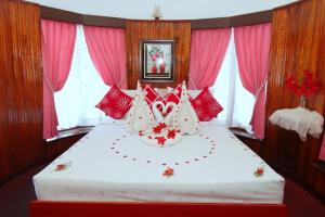 1 dormitorio con 1 cama grande con almohadas rojas y blancas en Heavenly Home Inn, en Nuwara Eliya