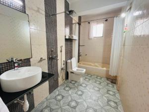La salle de bains est pourvue d'un lavabo, de toilettes et d'une baignoire. dans l'établissement Nagas Hotel Satyavati Morjim, à Morjim