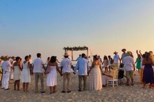 een groep mensen die rond een huwelijksceremonie op het strand staan bij CasaPiedra in Puerto Escondido