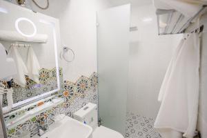 La salle de bains blanche est pourvue d'un miroir et de toilettes. dans l'établissement Mahalla old city, à Samarcande