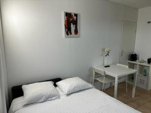 ein weißes Schlafzimmer mit einem Bett und einem Tisch in der Unterkunft Residence Vue Chateau in Neuenburg
