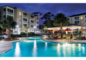 a swimming pool in front of a hotel at night at Myrtle Beach Bike Week - Spring Rally - Deluxe Studio Villa Retreat Resort - Special Offer Now! in Myrtle Beach