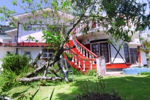 una casa con un árbol desarraigado delante de ella en Heavenly Home Inn, en Nuwara Eliya