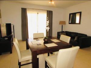 uma sala de estar com uma mesa de madeira e cadeiras brancas em Poolside Serenity at Tortuga Beach - 491 em Prainha