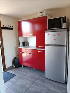 eine Küche mit roten Schränken und einer Mikrowelle auf dem Kühlschrank in der Unterkunft L'Appart de Karine et Nico in Gruissan