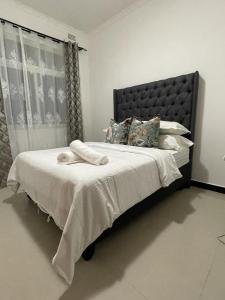 a bedroom with a large bed with white sheets and pillows at Silverest Sanctuary: Home away from Home in Lusaka