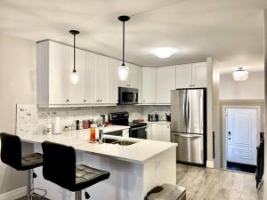 a kitchen with white cabinets and a stainless steel refrigerator at Hillside Villa - Trenton in Trenton