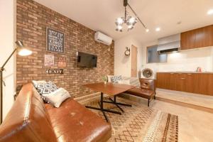 sala de estar con sofá de cuero marrón y mesa en Minowa House - Vacation STAY 61237v, en Tokio