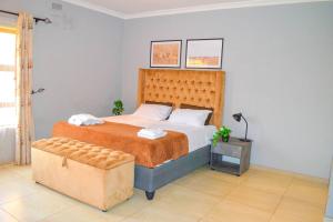 Kingsmead的住宿－Mt Pleasant - 4-Bed Villa in Harare Solar Power，一间卧室配有一张大床和一张搁脚凳