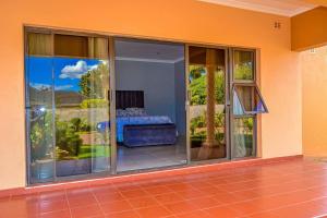 Mt Pleasant - 4-Bed Villa in Harare Solar Power في Kingsmead: غرفة بها أبواب زجاجية منزلقة مع سرير
