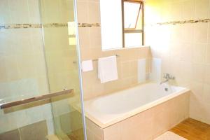 y baño con bañera y ducha acristalada. en Mt Pleasant - 4-Bed Villa in Harare Solar Power, en Kingsmead