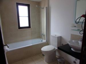 a bathroom with a toilet and a tub and a sink at Poolside Serenity at Tortuga Beach - 491 in Prainha