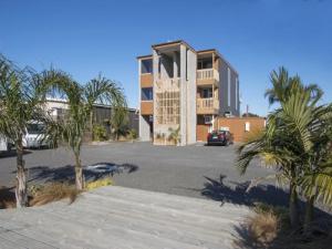 a building in a parking lot with palm trees at Beach Pacific Apartments in Waihi Beach