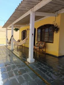 Casa aconchegante beira mar في مونغاغوا: شرفة مع أرجوحة على المنزل