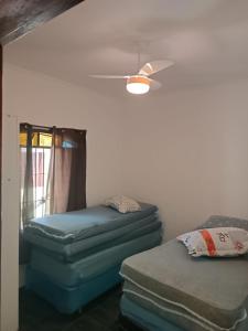 a room with two mattresses and a ceiling fan at Casa aconchegante beira mar in Mongaguá