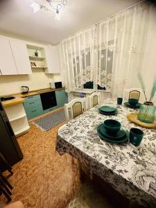 ein Esszimmer mit einem Tisch und einer Küche in der Unterkunft ЖК Трилистник in Qaraghandy
