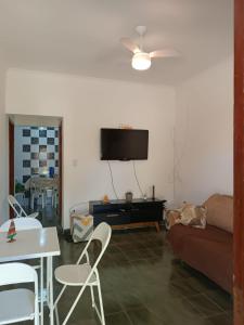 uma sala de estar com um sofá e uma televisão na parede em Casa aconchegante beira mar em Mongaguá