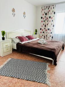 ein Schlafzimmer mit einem großen Bett und einem Teppich in der Unterkunft ЖК Трилистник in Qaraghandy