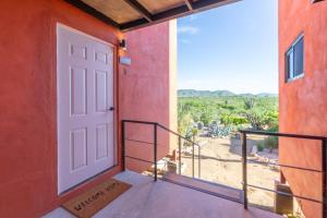 Pescadero的住宿－EXPERIENCE，红色建筑的白色门,设有阳台