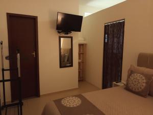 a bedroom with a bed and a television on the wall at Flats Casa Verde in Saquarema