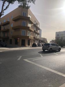 a car driving down a street in front of a building at Room in Trilithon Court Apartments Ghaxaq in Hal Ghaxiak