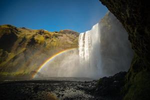a rainbow in front of a waterfall at Hótel Skógafoss by EJ Hotels in Skogar