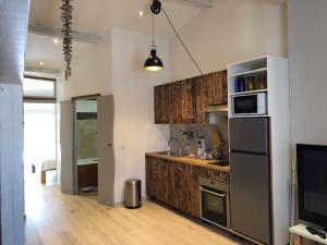 ル・ボーセにあるKembali mini loftのキッチン(ステンレス製の電化製品、木製キャビネット付)