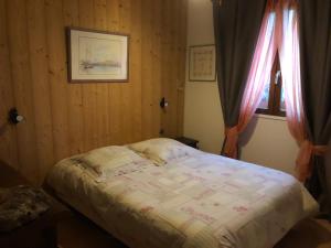 1 dormitorio con 1 cama y una ventana con cortinas en Chambre d’hôtes, en Les Chapelles