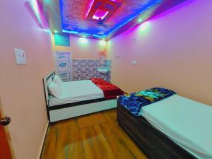 two beds in a room with purple lights at Ayodhya Residency 5 min walking from Ram Janmabhoomi in Ayodhya