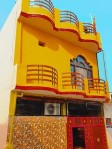 a yellow building with a balcony and red doors at Ayodhya Residency 5 min walking from Ram Janmabhoomi in Ayodhya