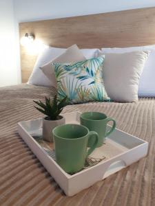 a tray with two cups and a plant on a bed at Milmari Lux Apartment N74 Kopaonik in Kopaonik