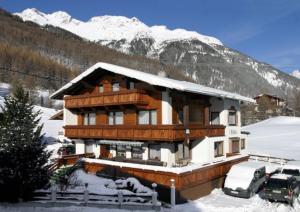 ein Haus im Schnee mit davor geparkt in der Unterkunft Haus Fridolin in Sölden
