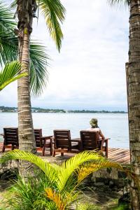 eine Person, die auf einer Bank am Wasser sitzt in der Unterkunft PirateArts Experience Resort in Bocas del Toro