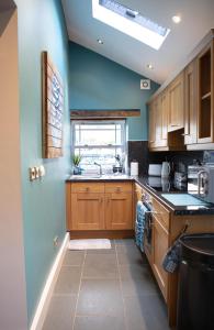 a kitchen with wooden cabinets and a blue wall at Vineyard Country Cottage in Llanerch-Aeron