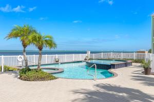 a swimming pool with palm trees and the ocean at Las Joyas Bayview Home in Port Isabel