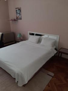 uma cama grande com lençóis brancos e almofadas em Anka em Jagodina