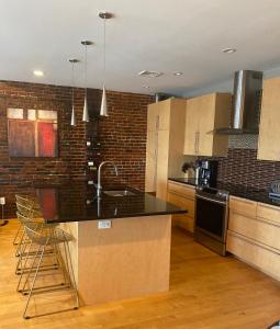 cocina con encimera negra y pared de ladrillo en Boston North end Harbor View condo. FREE PARKING, en Boston