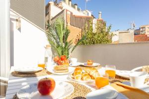a table with plates of food and fruit on a balcony at Duplex with terrace near Bcn in Terrassa