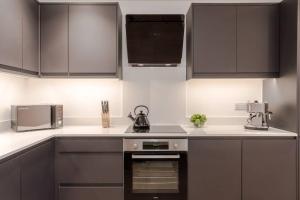 a kitchen with black cabinets and a stove top oven at The Ladywell in Lewisham in London