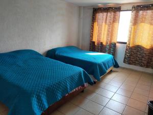 two beds in a room with blue comforter at Ubicacion Privilegiadadepartamento En El Centro in Almoloya de Juárez