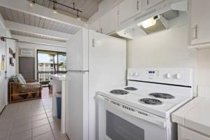 a white kitchen with a stove and a refrigerator at Kona Bali Kai Unit 362 Partial Ocean View Studio in Kailua-Kona