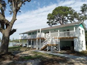 a large white house with a tree in front of it at Studio with Private Beach on Bayou Grande in Pensacola